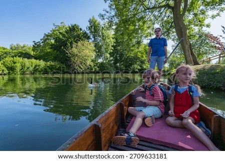 A sunny excursion on the river, with a man steering and two children relaxing in a boat visiting Oxford, England