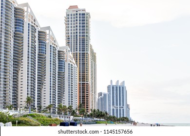 Sunny Isles Beach, USA - May 7, 2018: Apartment Condo Hotel Pinnacle Building Balconies During Sunny Day In Miami, Florida With Skyscrapers Urban Exterior In Evening, People On Sand