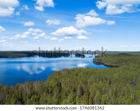 Sunny landscape in Finland with beautiful lake, forest and blue sky with some clounds. Amazing scandinavian nature, travel and hiking tourism destination.