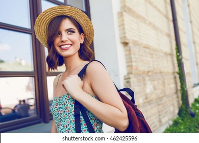 Sonniges Lifestyle-Modeporträt von jungen, stylischen Hippierinnen, die auf der Straße spazieren gehen, trendige Outfit tragen, Strohhut, mit Rucksack reisen.