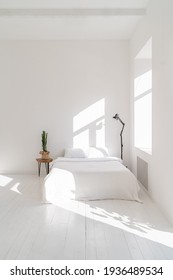 Sunny morning in Clean and stylish white bedroom interior. cactus standing on wooden table and black lamp on another side. Empty white copy space. Basic design. rustic or Scandinavian style. Vertical 