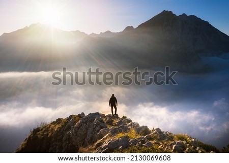 Sunny morning. Hiker stand on the top of mountain. View over misty and foggy morning valley.