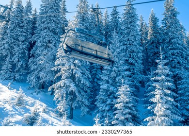Sunny morning in the winter forest. Empty cabin of a ski chair lift. A lot of snow on the tree branches