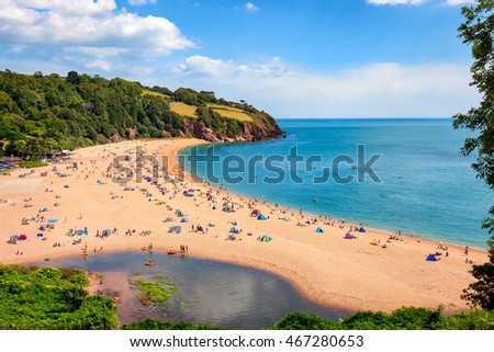 A sunny seascape with people enjoying the beach in Blackpool Sands, Devon.