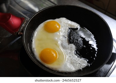 sunny side up eggs on a black frying pan on a gas stove. telur ceplok or mata sapi. - Powered by Shutterstock