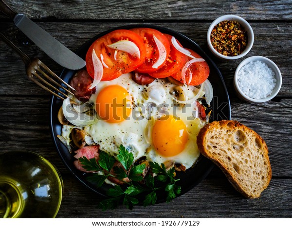 Sunny side up eggs with spinach, toasted bread\
and sausages on wooden\
table\
