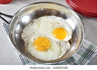 Sunny side up fried eggs in a stainless steel frying pan - Powered by Shutterstock