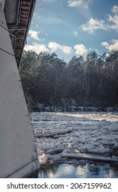 Sunny Spring Day And Ice Melting In A River. Large Concrete Block Of Pedestrian Bridge, March Weather In The City. Selective Focus On The Debacle, Blurred Background.