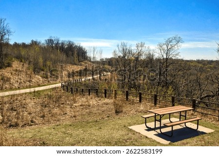 Sunny Spring landscape view of a picnic table and fence along the Mississippi River Greenway Trail near Hastings, Minnesota.