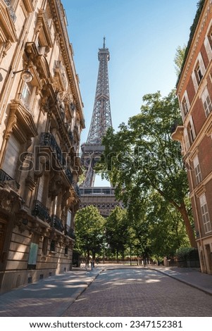 Sunny street view of the Eiffel Tower in Paris during summer, with people walking around.