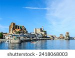 Sunny view of Castro Urdiales in Cantabria, featuring its iconic church and lighthouse by the harbor with boats.