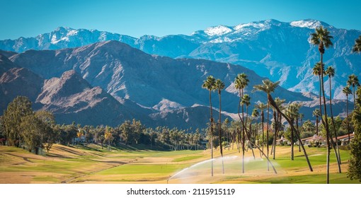 Sunny Warm Winter Time in the Palm Desert Coachella Valley. Golf Courses, Palms and Mountains Covered by Fresh Snow. Recreation in Southern California State, United States of America.