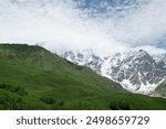 In sunny weather, green fields and snowy hills. Snowy mountain landscapes in spring in Svaneti.Magnificent mountain landscapes of Georgia.