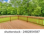 Sunny Wooden Deck With Railing Overlooking Lush Green Backyard in Summer