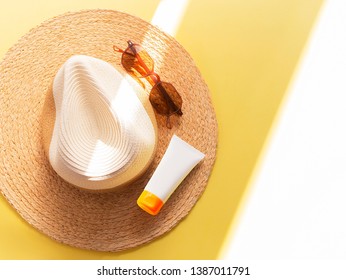 Sunprotection objects. Straw woman's hat with sun glasses and protection cream spf 30 top view on bright yellow background. Beach accessories. Summer Travel Vacation Concept. Sale kit. Copy space. 