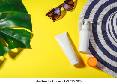 Sunprotection objects. Straw woman's hat with sun glasses and protection cream spf 30 top view on bright yellow background. Beach accessories. Summer Travel Vacation Concept. Sale kit. Copy space.