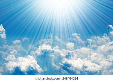Sunrays in blue sky with white clouds