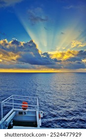 Sunrays escaping from the clouds during sunset at the Pacific Ocean, as viewed from the bridge wing of a merchant marine ship