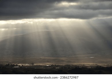 sunrays shinning through the cloud onto a small valley