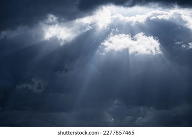 The sunrays through dense dark gray clouds