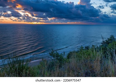 Sunrise At Baltic Sea Beach. Cloudy Weather, Small Waves, No People. Sun Flares And Water Reflection