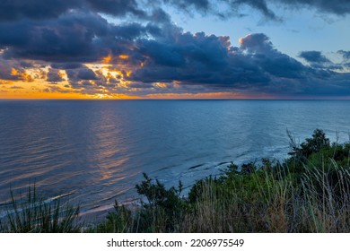 Sunrise At Baltic Sea Beach. Cloudy Weather, Small Waves, No People. Sun Flares And Water Reflection