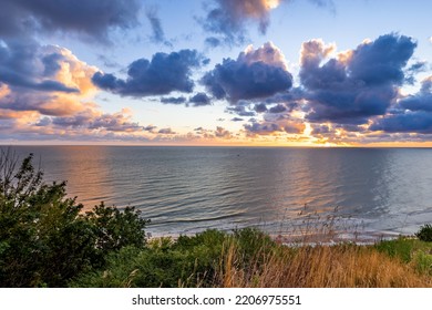 Sunrise At Baltic Sea Beach. Cloudy Weather, Small Waves, No People. Sun Flares And Water Reflection