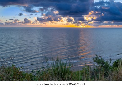 Sunrise At Baltic Sea Beach. Cloudy Weather, Small Waves, No People. Sun Flares And Water Reflection