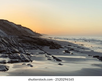 Sunrise Beach Craggy Rocks Hills Ocean Wet Sand - Powered by Shutterstock