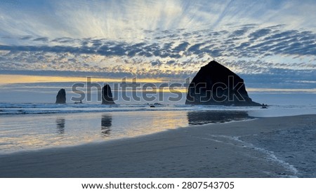 Sunrise at Cannon Beach with Haystack Rock reflected on wet sand