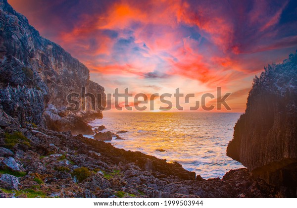 sunrise captured at the bluff in Cayman Brac\
in the Cayman Islands. The light from the sun has lit the rocky\
cliff face as well as the clouds\
above