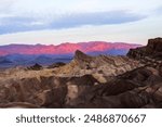 A sunrise captured in Death Valley National park. The park is located in California, on the border of Nevada. The pink pastels make the mountains in the distance glow behind the unique rock structures