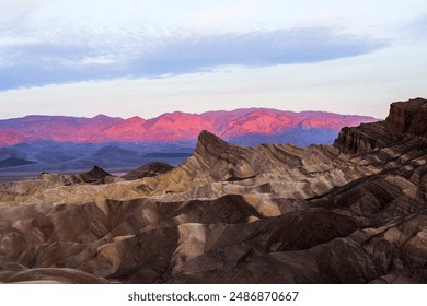 A sunrise captured in Death Valley National park. The park is located in California, on the border of Nevada. The pink pastels make the mountains in the distance glow behind the unique rock structures - Powered by Shutterstock