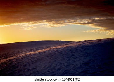 Sunrise casting an orange glow over sand dunes in White Sands National Park