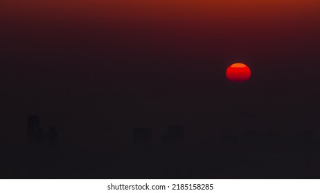 Sunrise Close Up View Over Dubai Skyline In The Morning, Aerial Top View From Dubai Marina Timelapse. Big Sun On Orange Sky Rise Over Fog Around Skyscrapers. United Arab Emirates