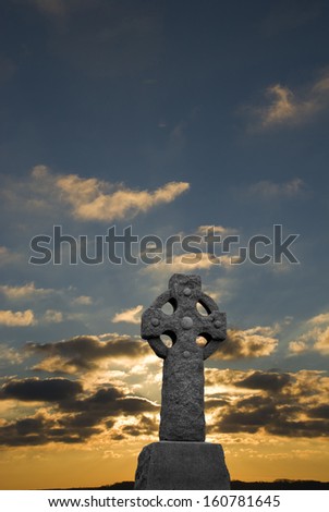 Sunrise with clouds with celtic cross in the foreground
