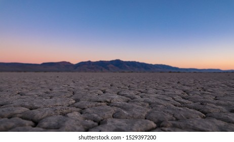 Sunrise in a desert. View of a cracked surface of Alvord desert with Steens mountains in the background 