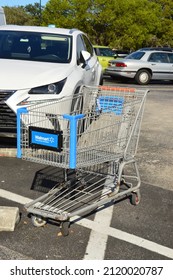 Sunrise, Florida, USA - December 22, 2021: Shopping Cart With Walmart Logo Parked Near Car In Parking Lot At Walmarts On The Corner Of N. University Dr And W Oakland Park Blvd In Sunrise Florida.