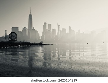 Sunrise in the fog in Jersey City looking across the Hudson River at a silhouette of downtown Manhattan skyline emerging from the fog right to left - Powered by Shutterstock