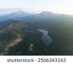 Sunrise illuminates Todd Lake and Three Sisters mountains, Oregon, during summer. These mountains and their surrounding forests, near Bend, provide exceptional hiking, biking, climbing, and camping.