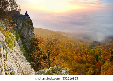 Sunrise with inversion above the deep autumn valley of mountains with small man on the top, who is watching this beautiful scenery - Powered by Shutterstock