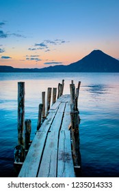 Sunrise Landscape Travel Photo Of Lake Atitlán In Guatemala.  View From Wooden Pier Over Water With View Of Volcano On The Horizon.