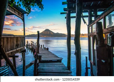 Sunrise Landscape Travel Photo Of Lake Atitlán In Guatemala.  View From Wooden Pier Over Water With View Of Volcano On The Horizon.