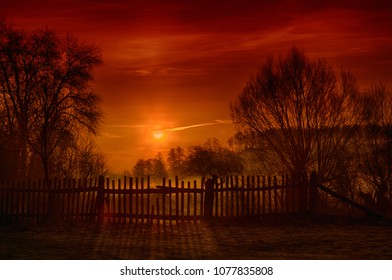 Sunrise with a light morning fog over an old wooden fence with trees - Powered by Shutterstock