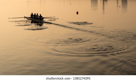 Sunrise lights up team of four rowers in canoe practicing in London Docklands - Powered by Shutterstock