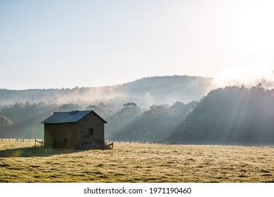 Sunrise Morning Silhouette Of Agricultural Abandoned Brick Storage Barn Shed In Autumn Landscape Farm Field In Rural Countryside Of West Virginia With Fog Mist Sun Sunrays By Rolling Hills