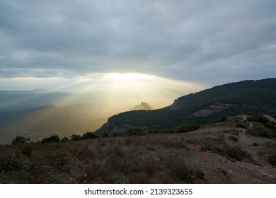 Sunrise From A Mountain With The Sun Breaking Through The Clouds Leaving A Beam Of Orange Light On The Landscape