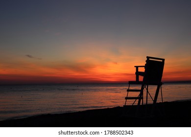 Sunrise on beach of Lake Erie with lifeguard chair in foreground in silhouette.   - Powered by Shutterstock