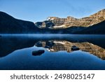 Sunrise on Cameron Lake, Waterton, Alberta Canada. Mist on water. Reflection