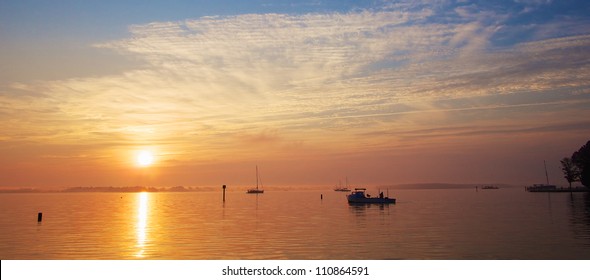 Sunrise On The Chesapeake Bay Coast With Crab Boat And Sail Boats